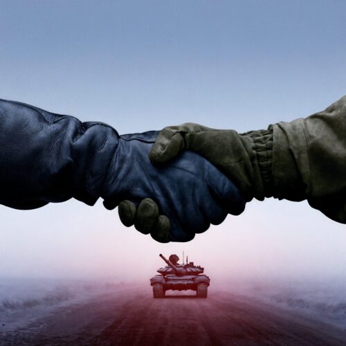 Poignée de main entre deux personnes en tenue militaire au-dessus d'un char d'assaut à l'horizon.
