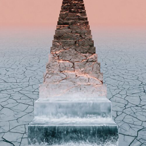Une structure pyramidale en pierre dressée au milieu d'un sol désertique et craquelé sous un ciel rosé.