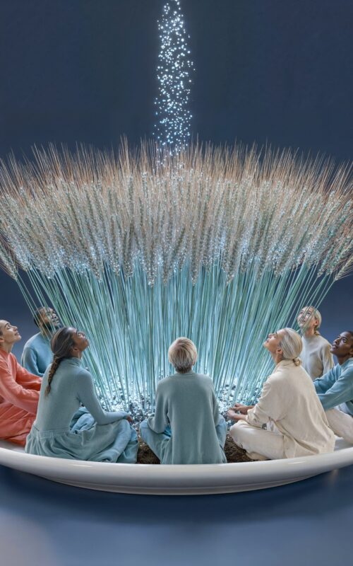 Un groupe de personnes assises en cercle autour d'un bouquet de blé d'où s'élève une colonne de lumière.