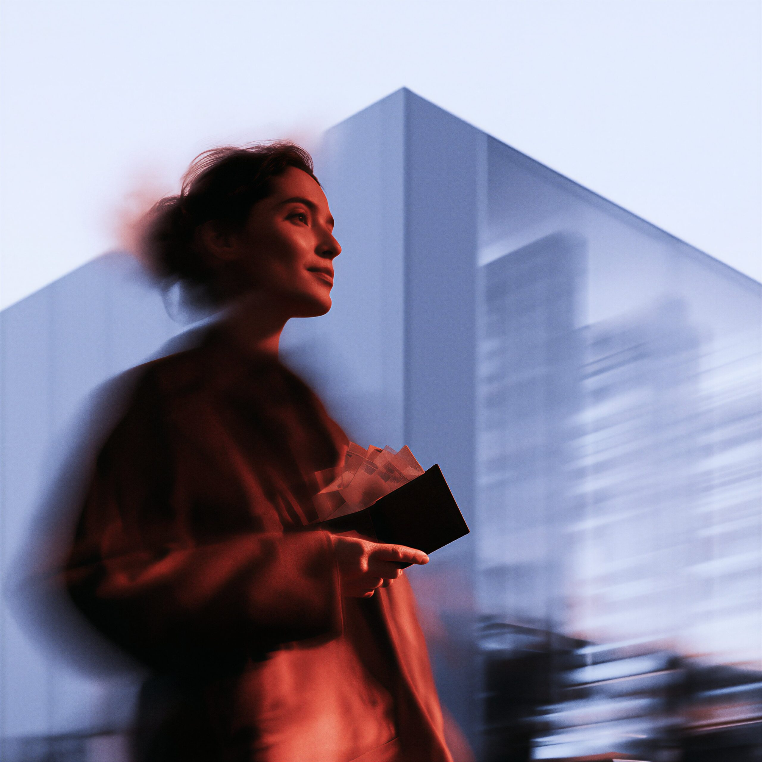 Une femme marchant dans la ville avec un effet de flou de mouvement, tenant un portefeuille ouvert.